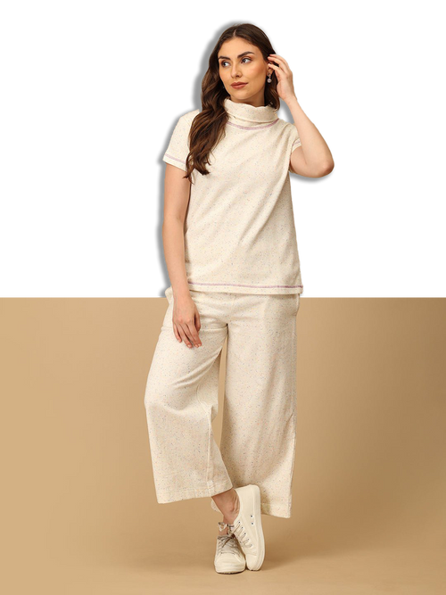 Woman wearing a beige co-ord set with a plain background