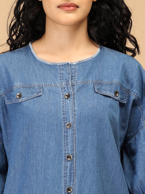 Close-up of women’s chambray dress showing round neckline, contrast stitching, and metal buttons.