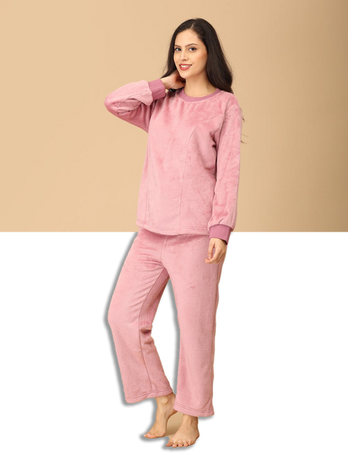 Woman wearing a pink pajama set against a beige background